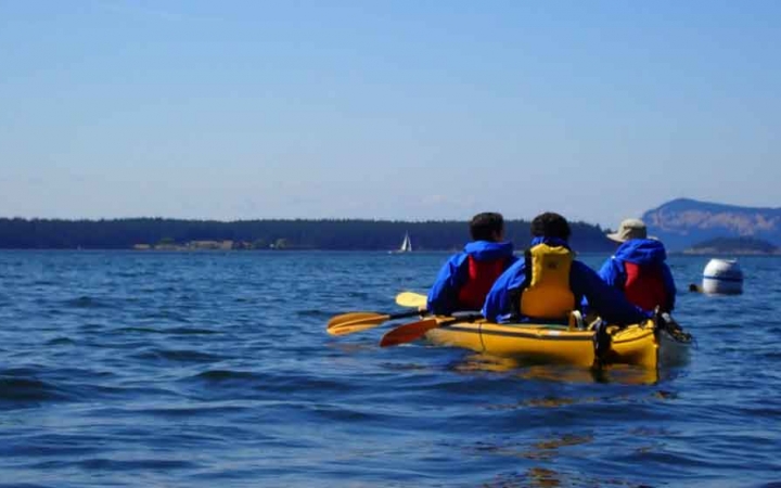 two kayaks are paddled on blue water on an outward bound expedition 